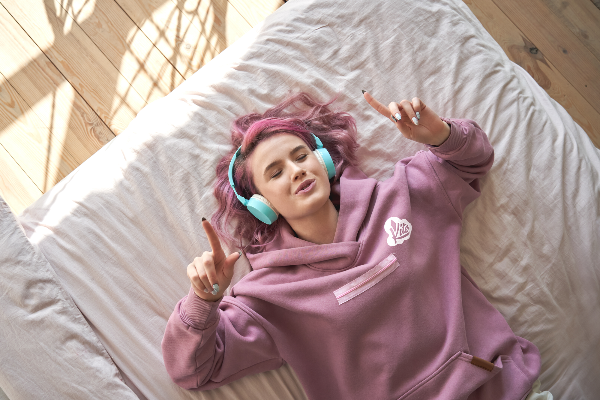 Lady wearing a Kite branded Hoodie with headphones listening to music.