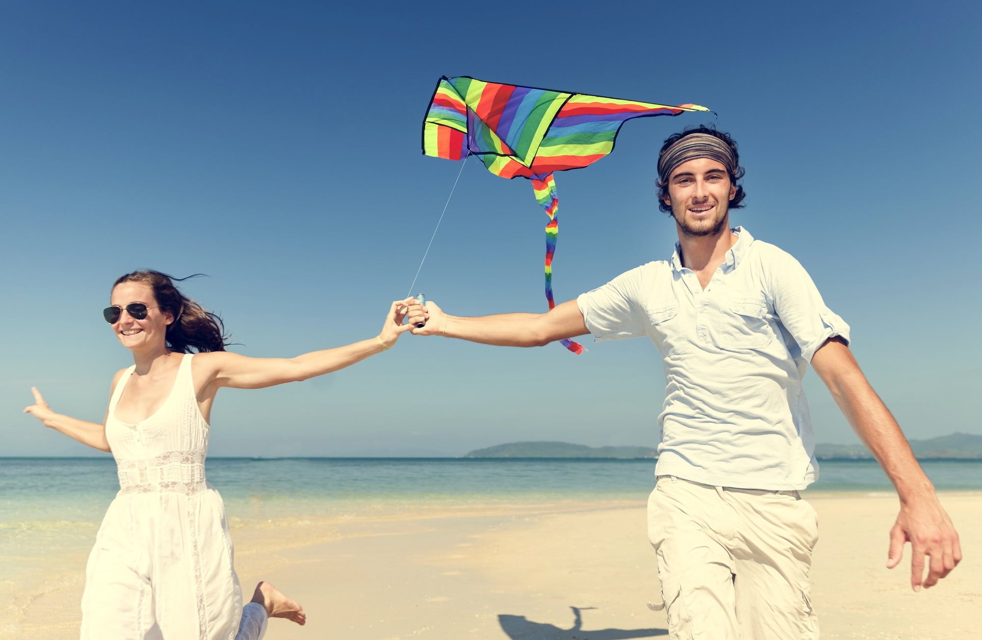 2 people on a beach flying a kite. they look stoned.